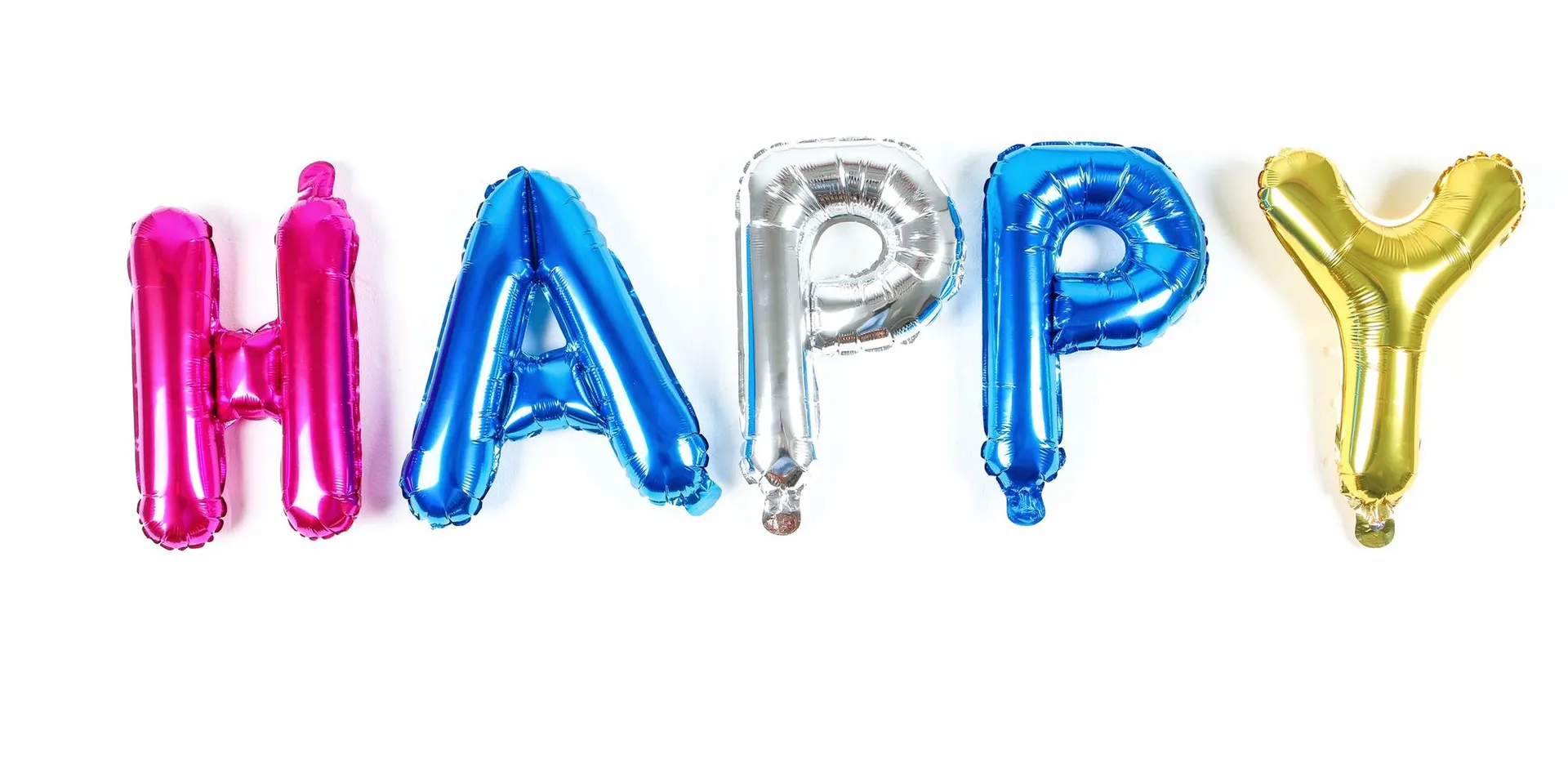 حروف معدنية ملوّنة تكتب HAPPY على خلفية بيضاء