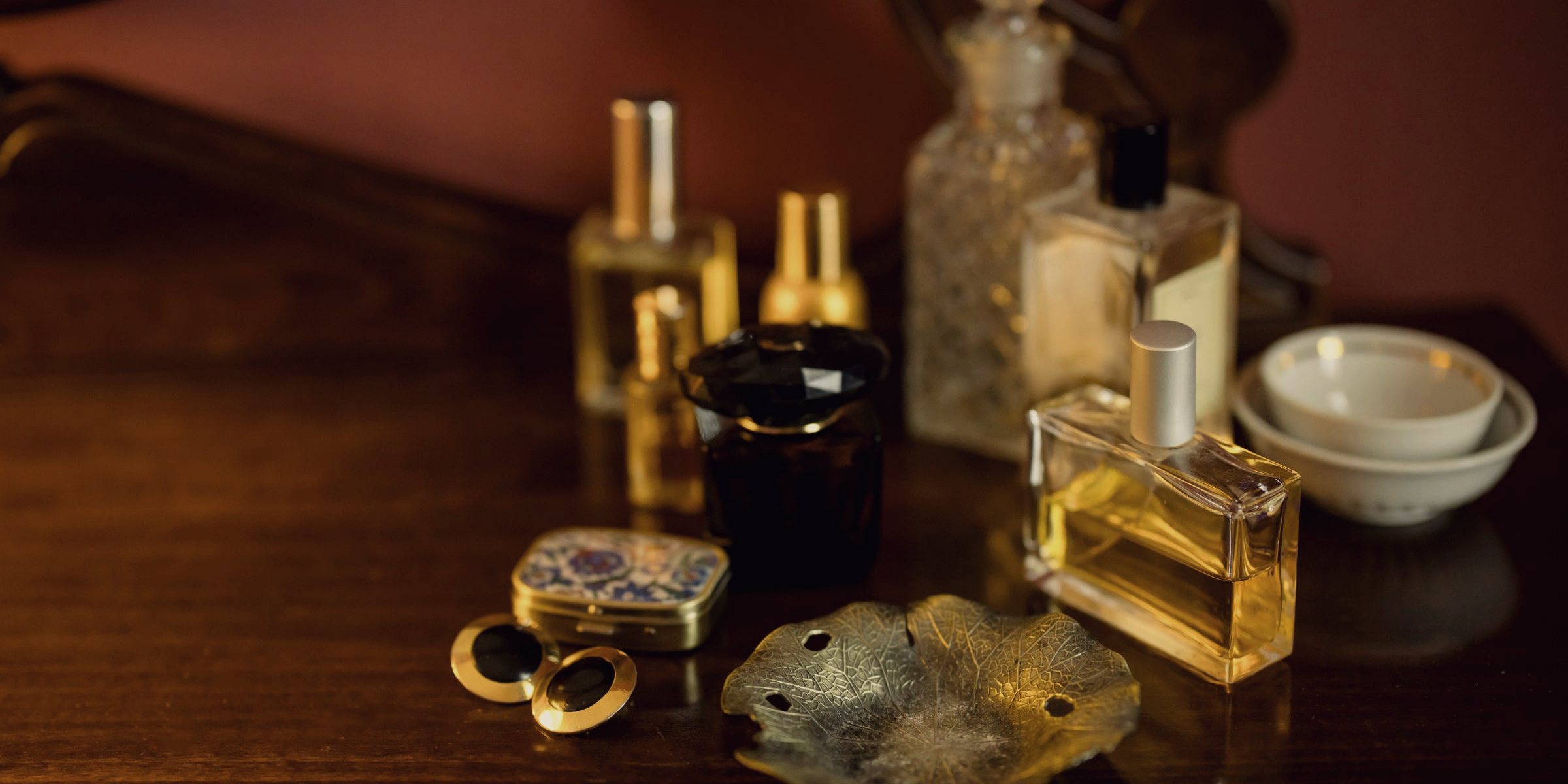 زجاجات عطر ومبخرة نحاس على سطح خشبي داكن